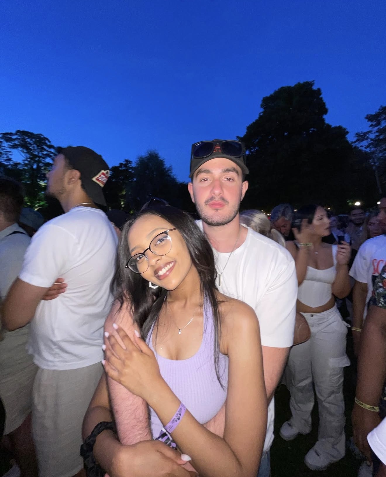 Two friends together in an outdoor crowd beneath a deep blue evening sky