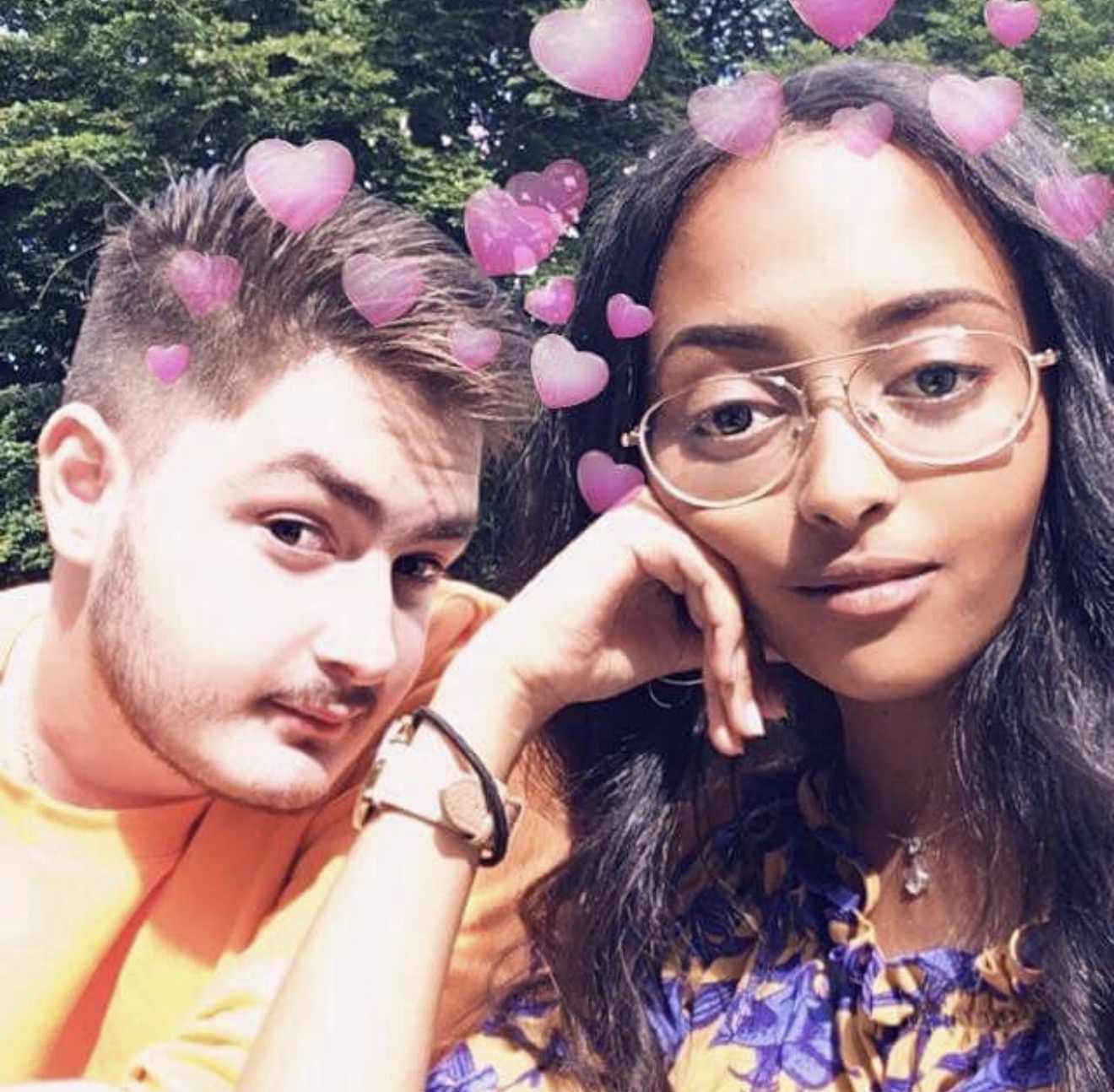 A sunny outdoor selfie of two friends with a pink hearts filter