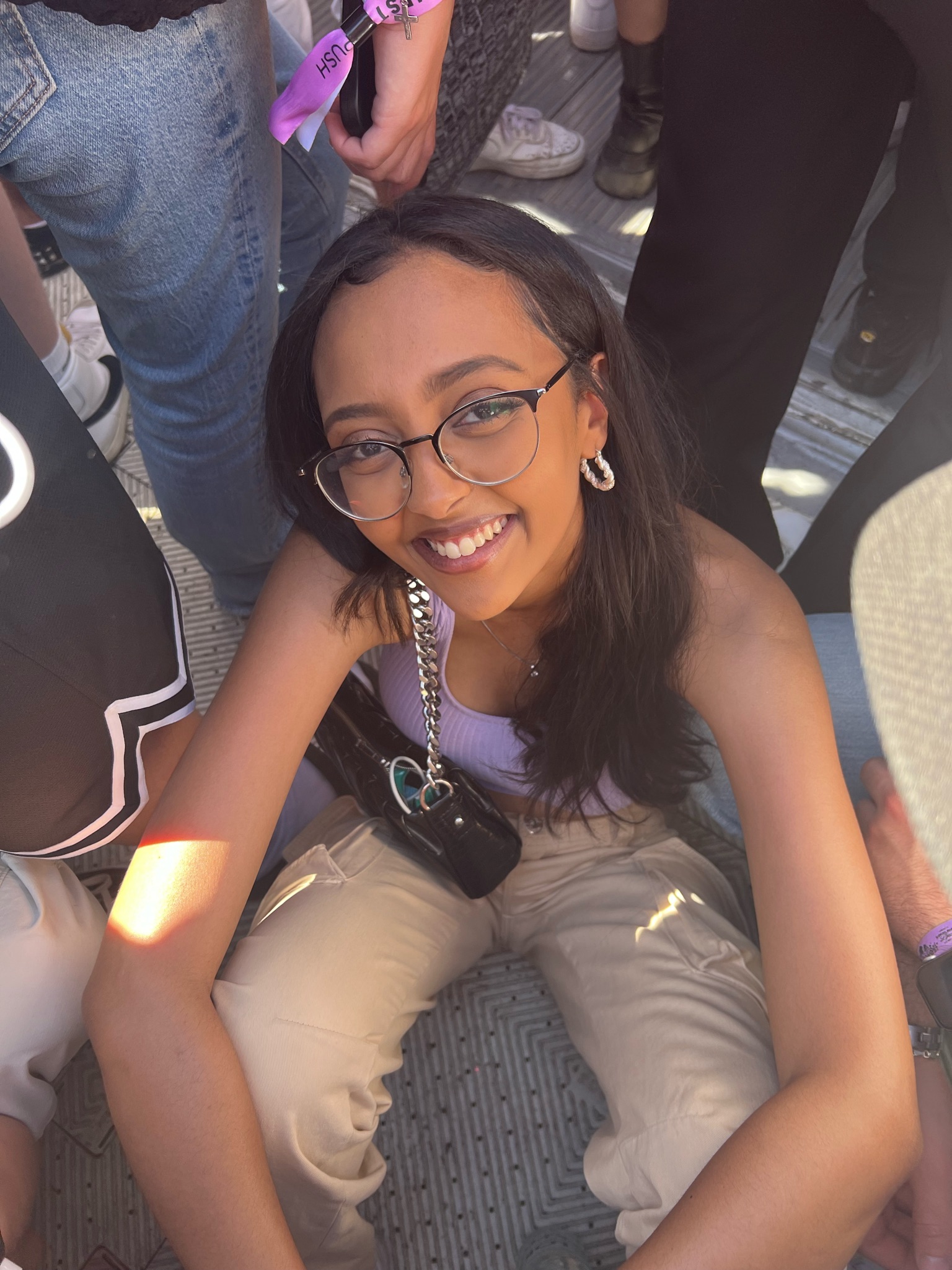 A smiling woman in glasses and a lilac top looking up at the camera