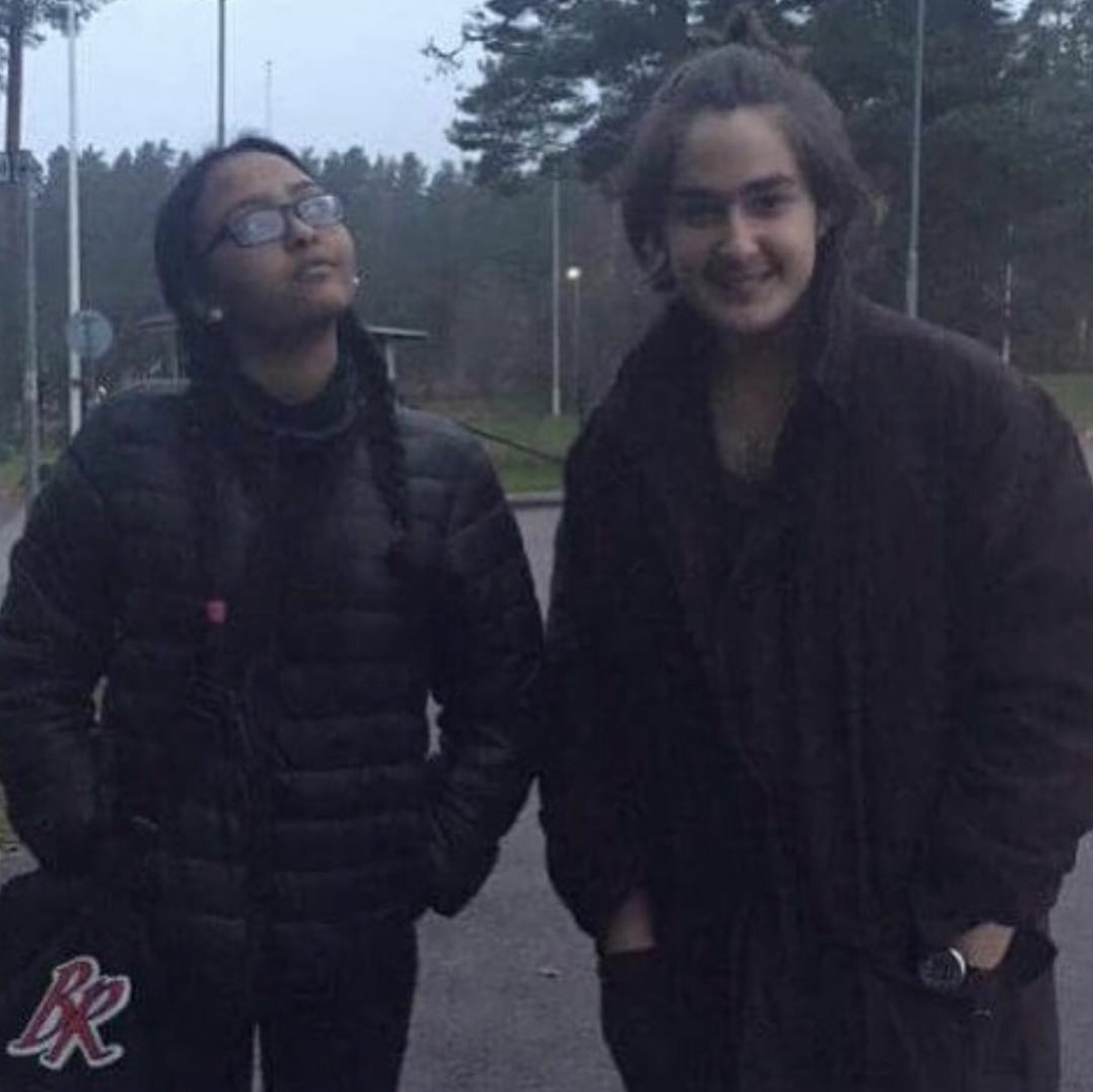 Two friends in dark jackets outdoors in an older photograph