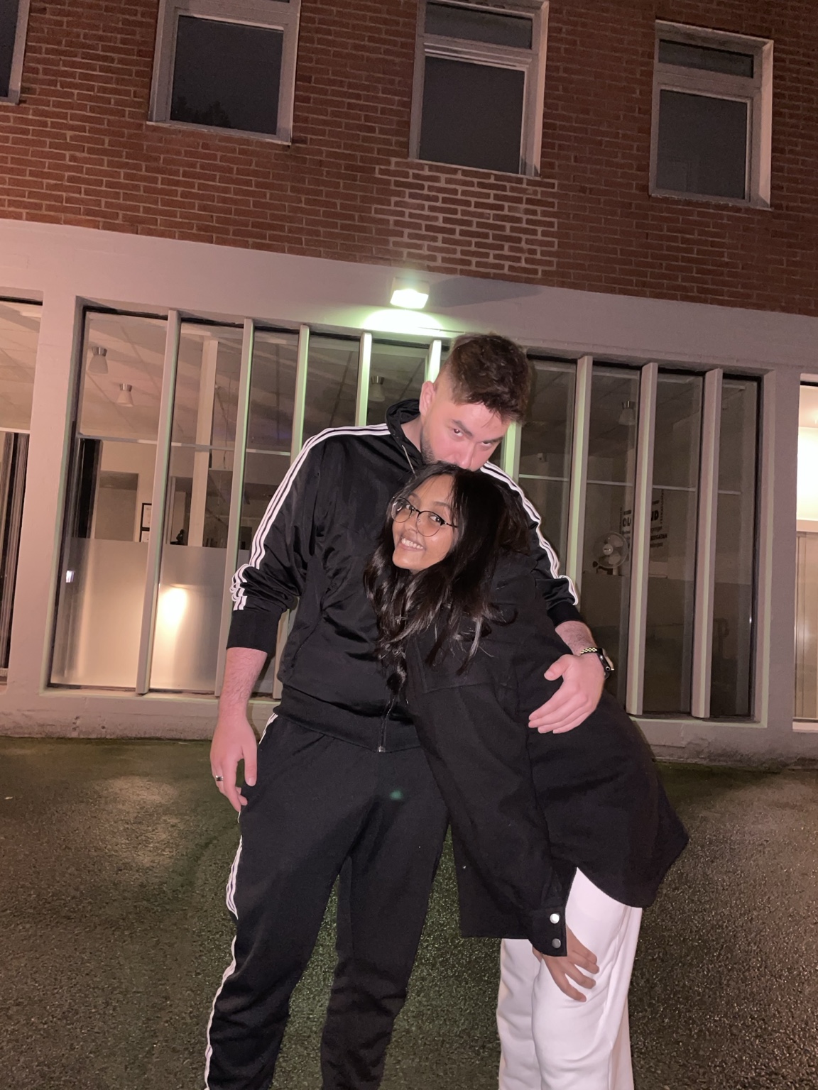 Two friends embracing outside a brick building at night