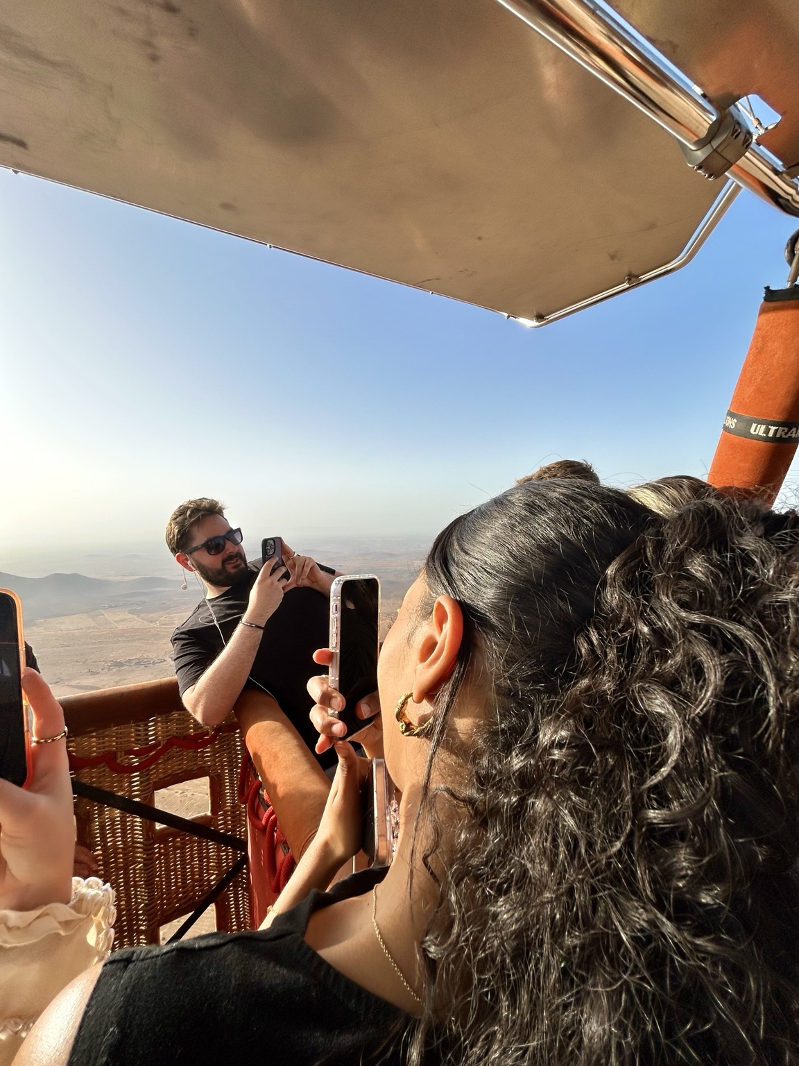 Friends taking photographs from inside a hot-air balloon basket